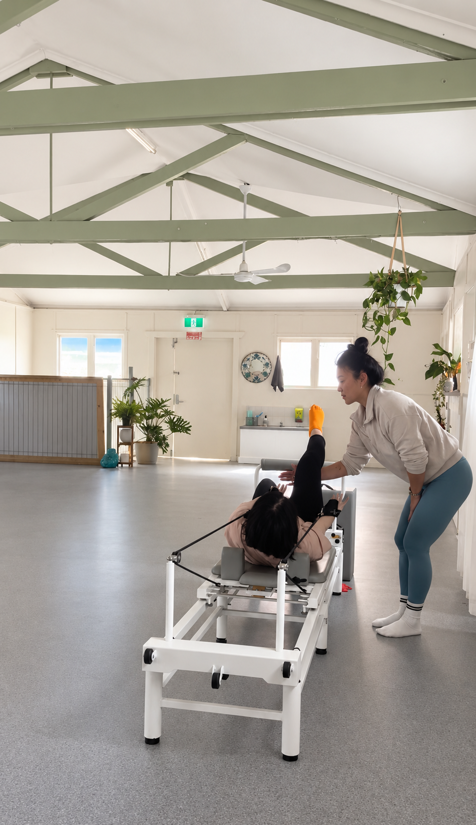 An instructor guiding a student through a Pilates reformer exercise