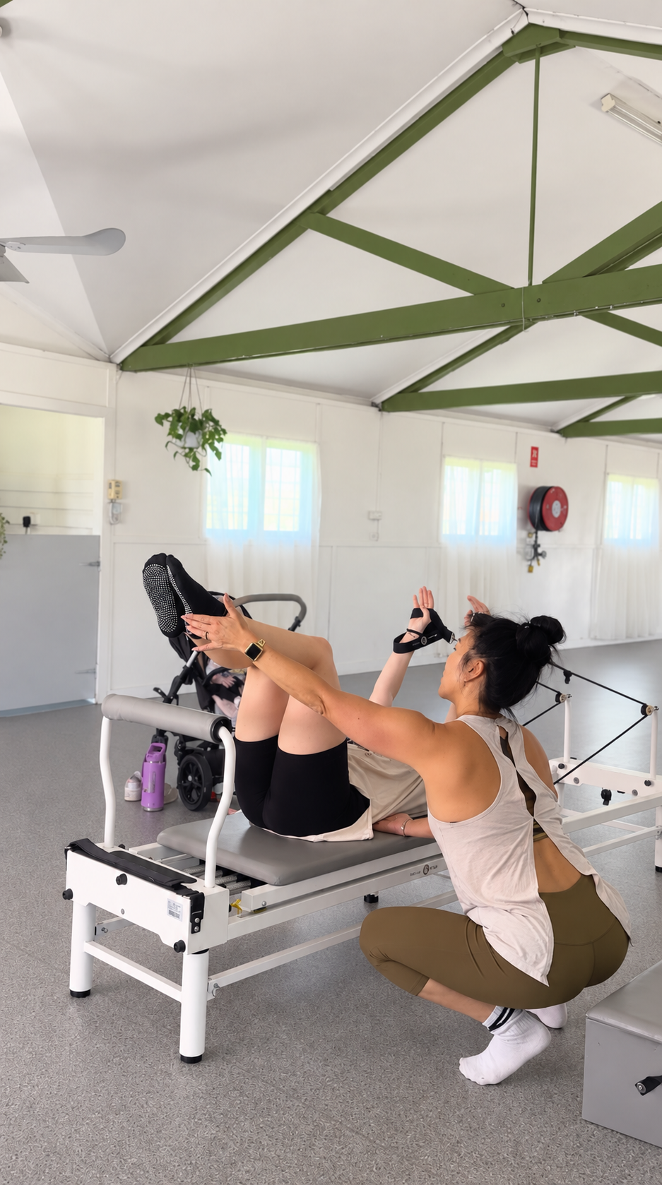 A Pilates instructor guiding a student through a reformer movement